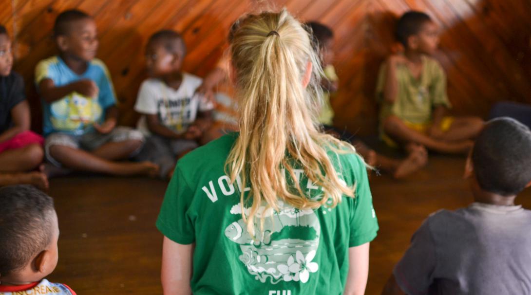 Durante su voluntariado social para jóvenes, una voluntaria ayuda en clases en Fiyi. Voluntaria internacional ayudando a niños durante sus clases en Fiyi.